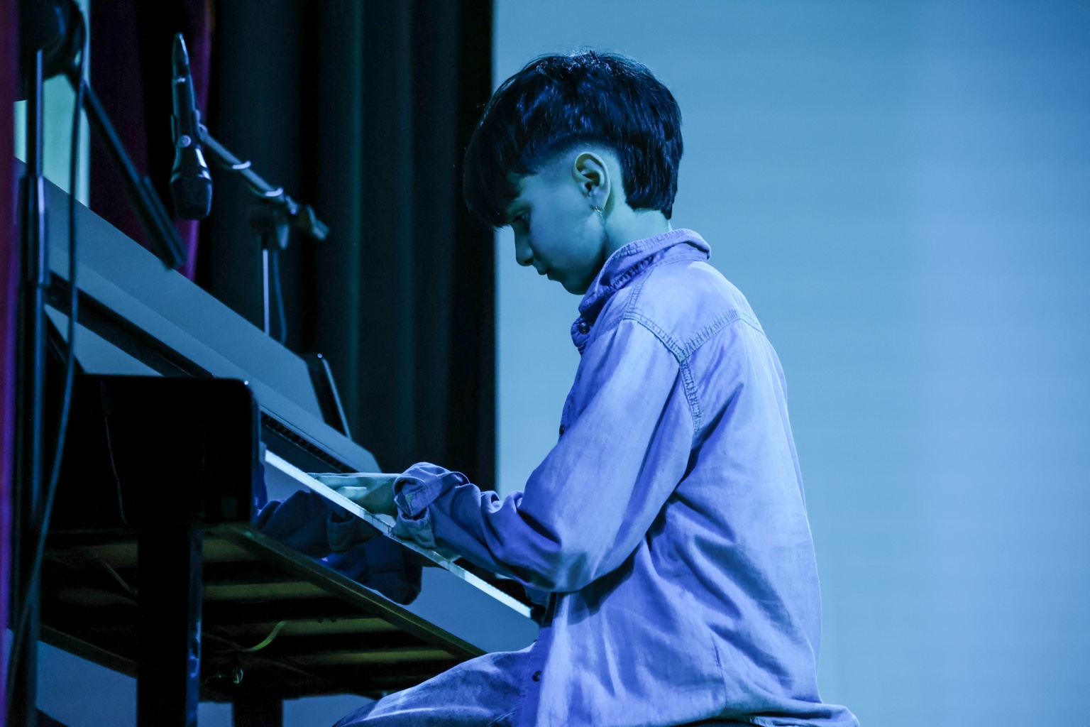 Edoardo Rossi, in arte Eddy, polistrumentista al pianoforte sotto le luci blu del palco